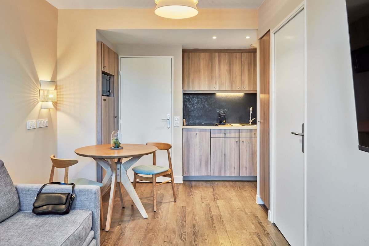 Un espacio habitable compacto con comedor, kitchenette y sofá.