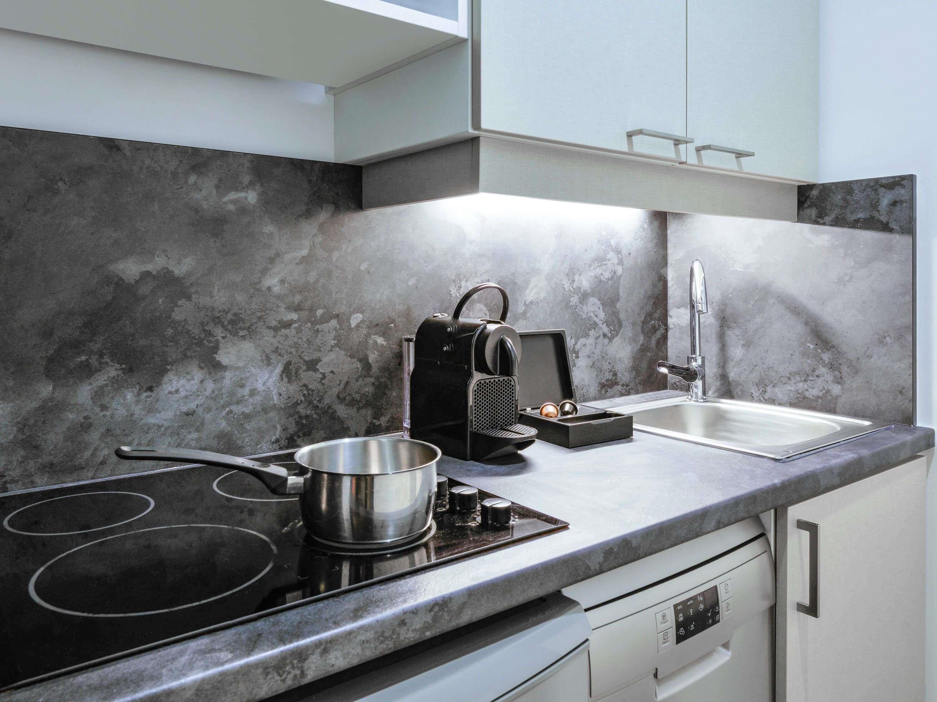 A modern kitchen with a stovetop, a coffee maker, a sink, and a dishwasher.