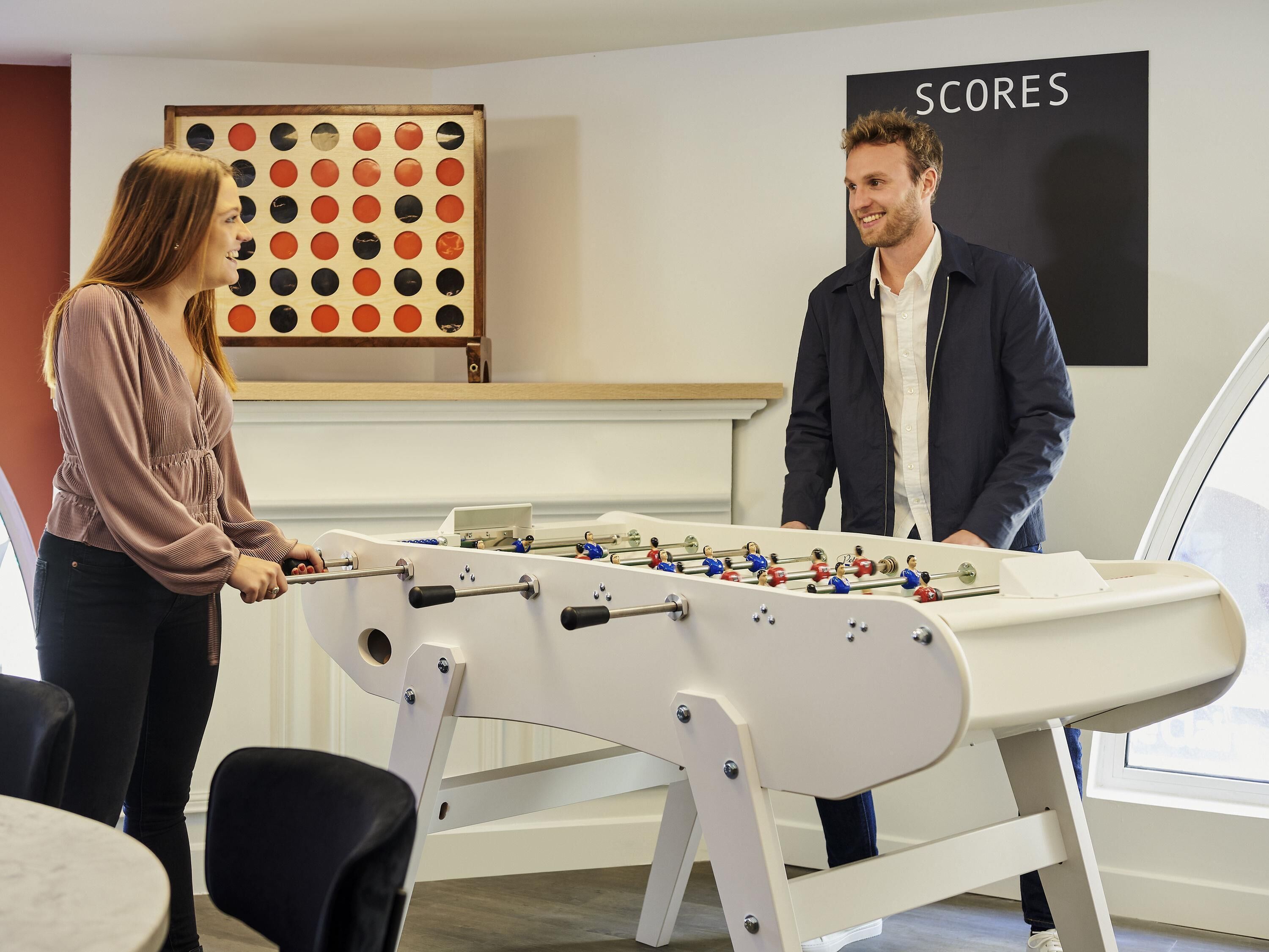 Een tafelvoetbaltafel in een ruimte met een bord waarop 'SCORES' staat.