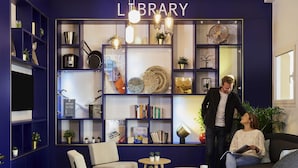 Una biblioteca con estanterías, una silla, una mesa y un sofá.