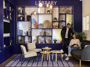Una biblioteca con estanterías, una silla, una mesa y un sofá.