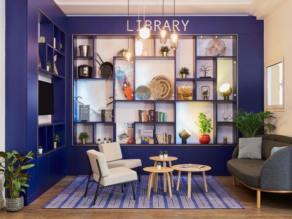 A library with bookshelves, a chair, two tables, and a sofa.