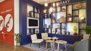 Una biblioteca con decoración azul y blanca, que incluye estanterías, un televisor de pantalla plana y zonas de estar.