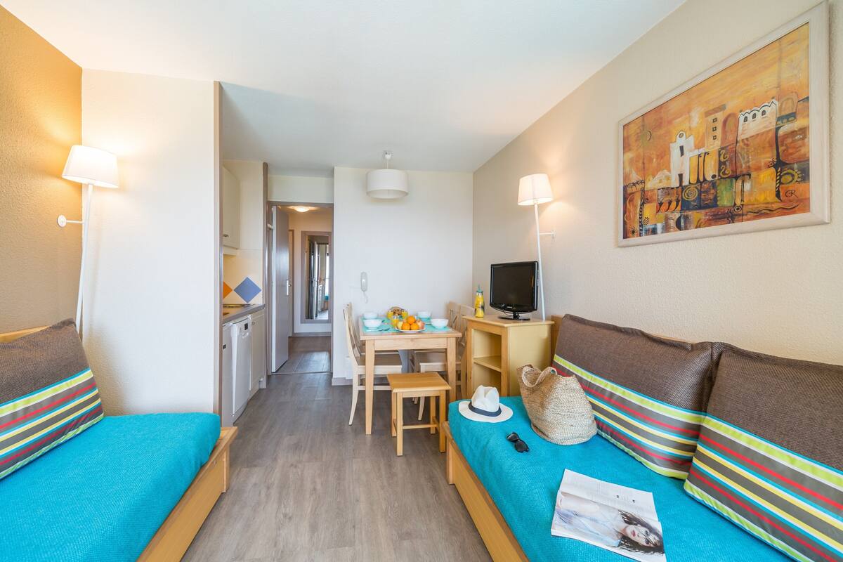 Hotelkamer met een bed, een bank, een bureau met computer, een stoel en een eettafel met stoelen.