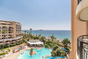 Un complexe hôtelier doté d’une grande piscine, de palmiers et offrant une vue sur l’océan.
