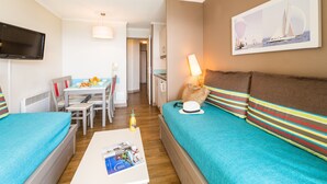 Ein Hotelzimmer mit Bett, Sofa, Esstisch und Fernseher.