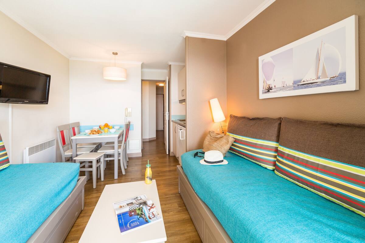 Een hotelkamer met een bed, een bank, een eettafel en een televisie.
