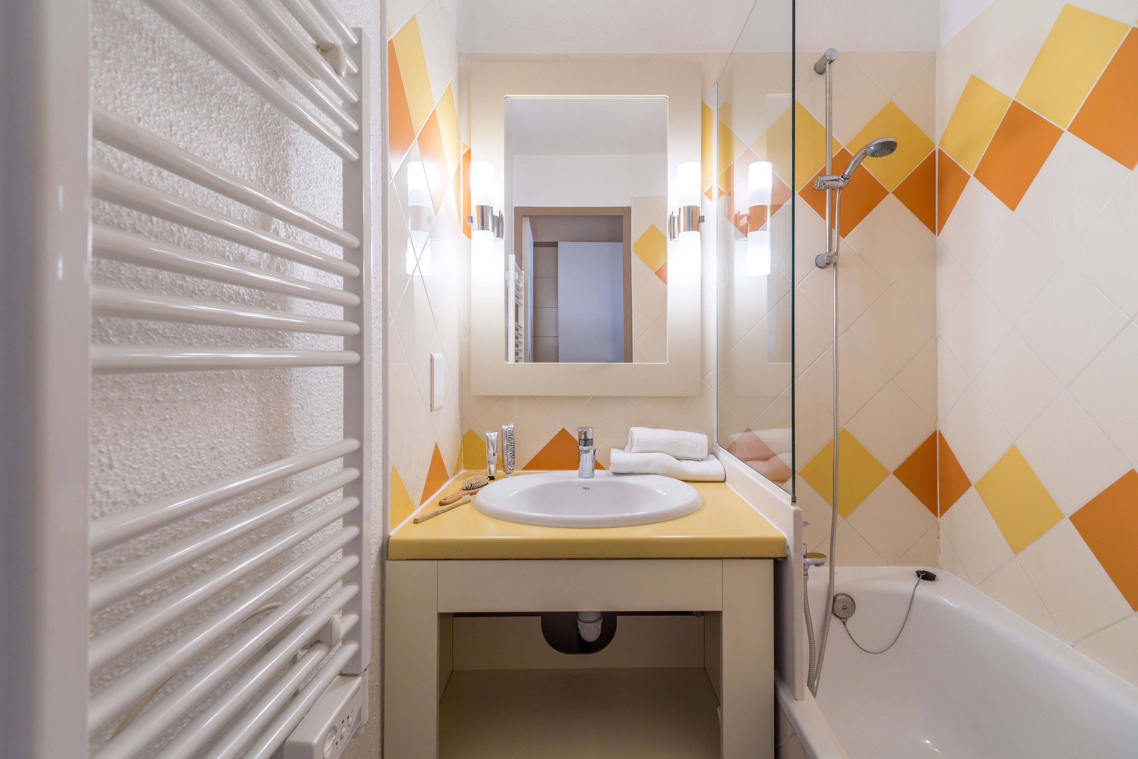 Un bagno con termosifone bianco, lavandino, specchio e doccia.