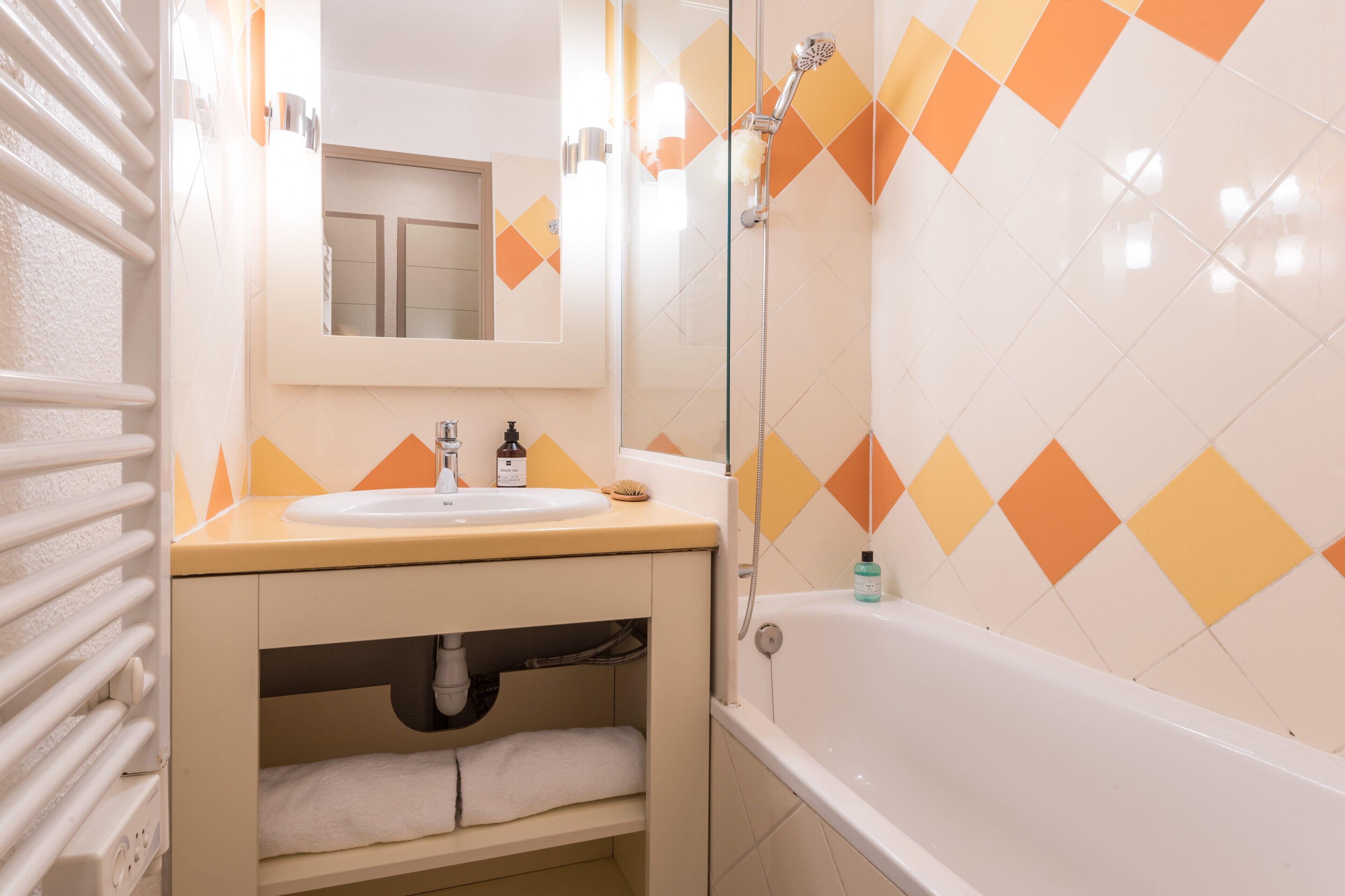 A bathroom with a sink, mirror, and bathtub.