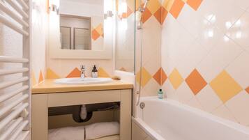 A bathroom with a sink, mirror, and bathtub.