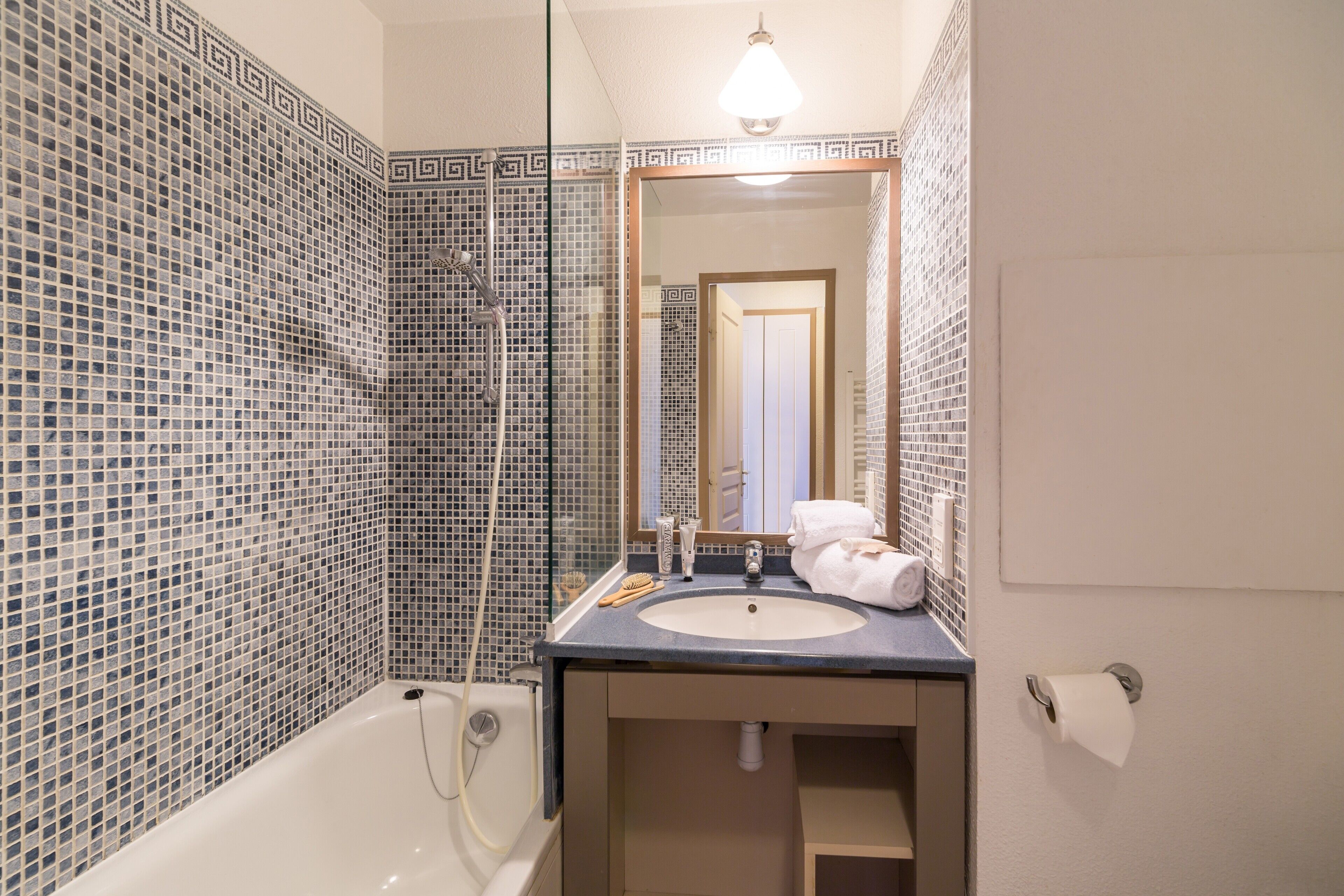 A bathroom with a bathtub, sink, and mirror.
