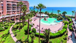 Ein Resort mit zentralem Pool, Palmen und einem Strand.