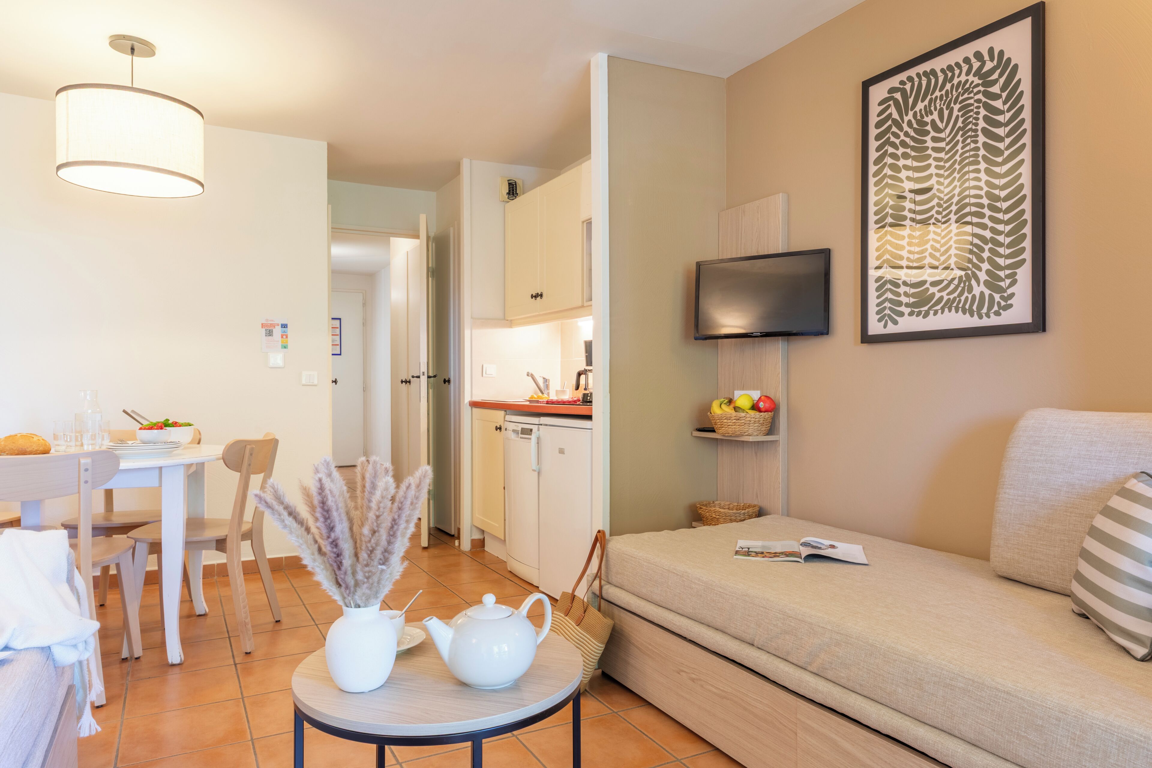 Una sala de estar moderna con un sofá, una mesa de comedor con sillas, una cocina y un televisor en la pared.