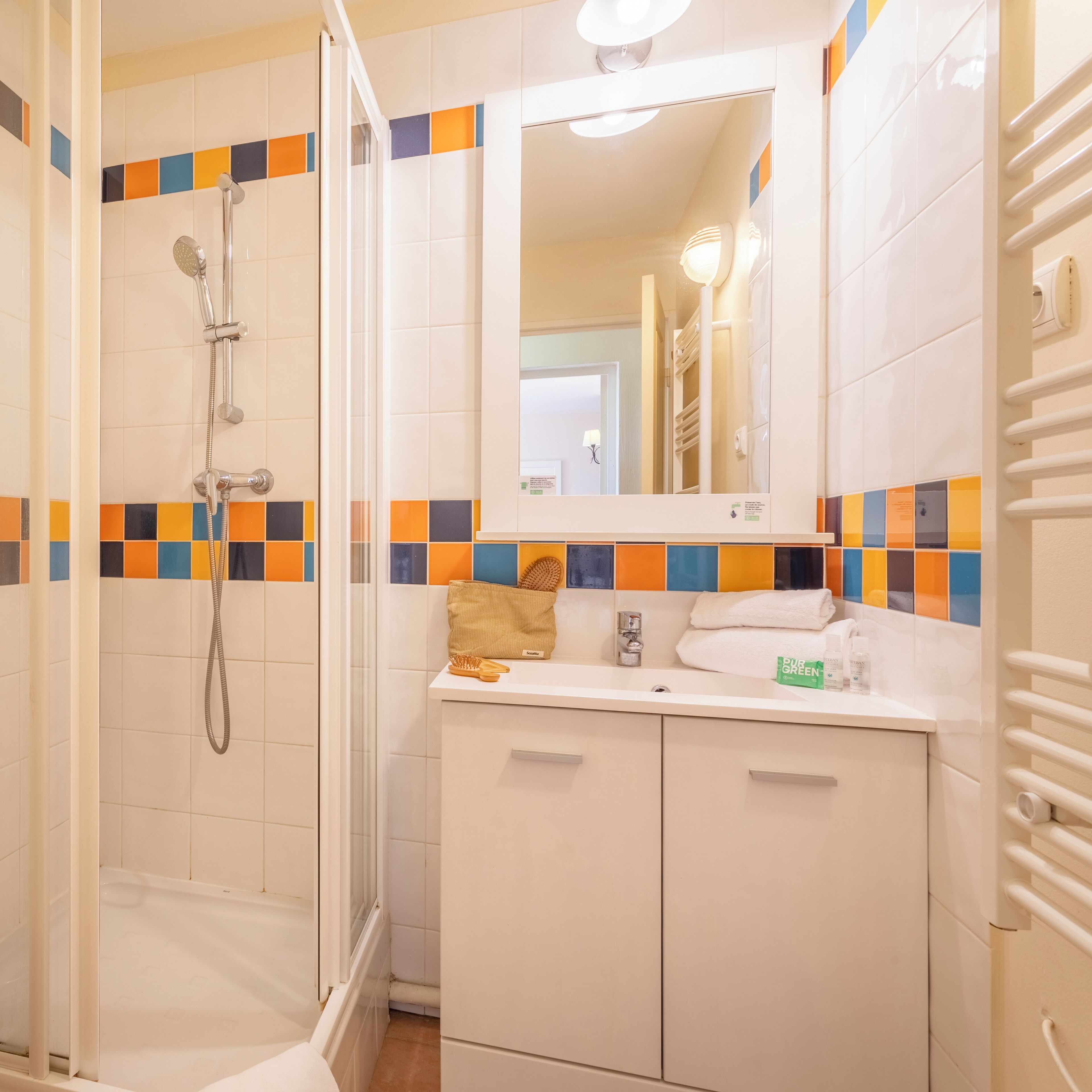 Une salle de bain avec une douche, un lavabo et un miroir.