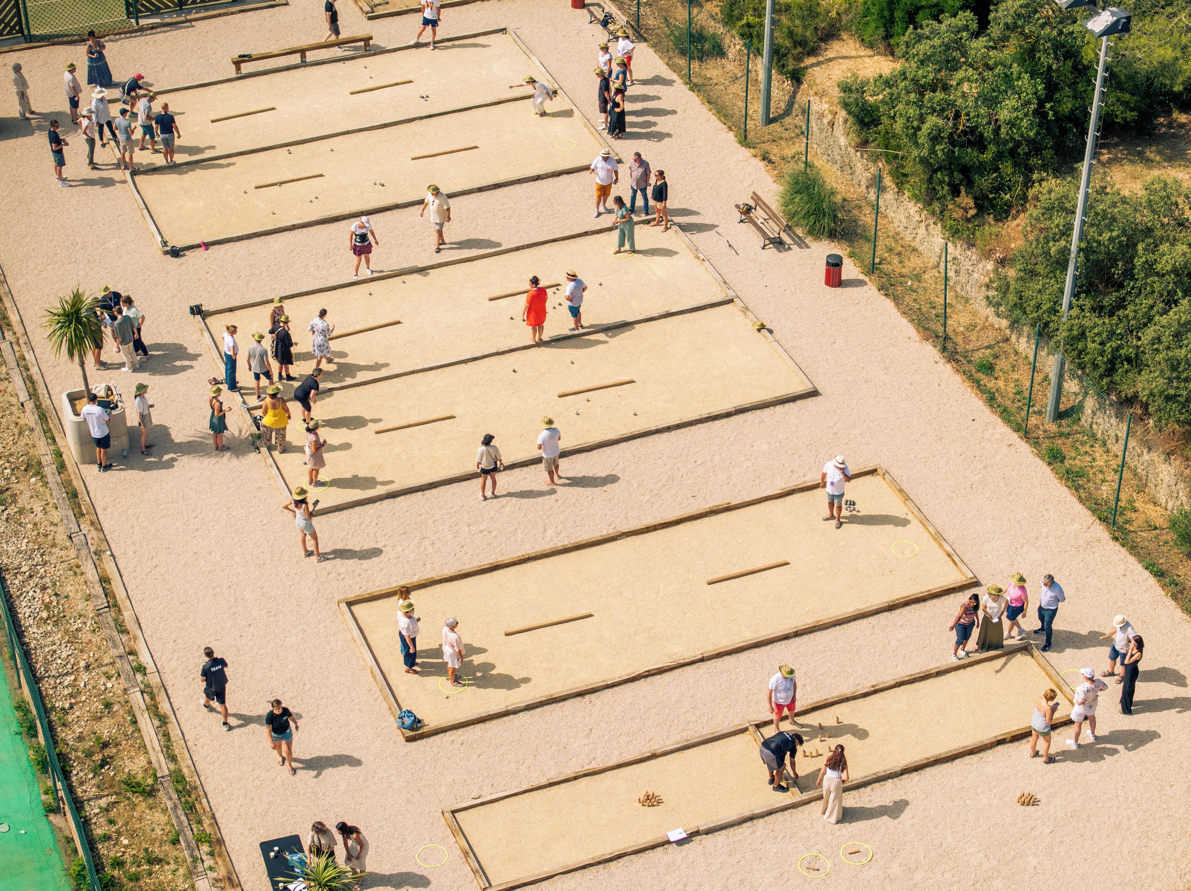 A sandy beach area with multiple rectangular sand courts, benches, and a trash bin.