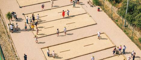 Un área de playa arenosa con varias canchas de arena rectangulares, bancos y un contenedor de basura.