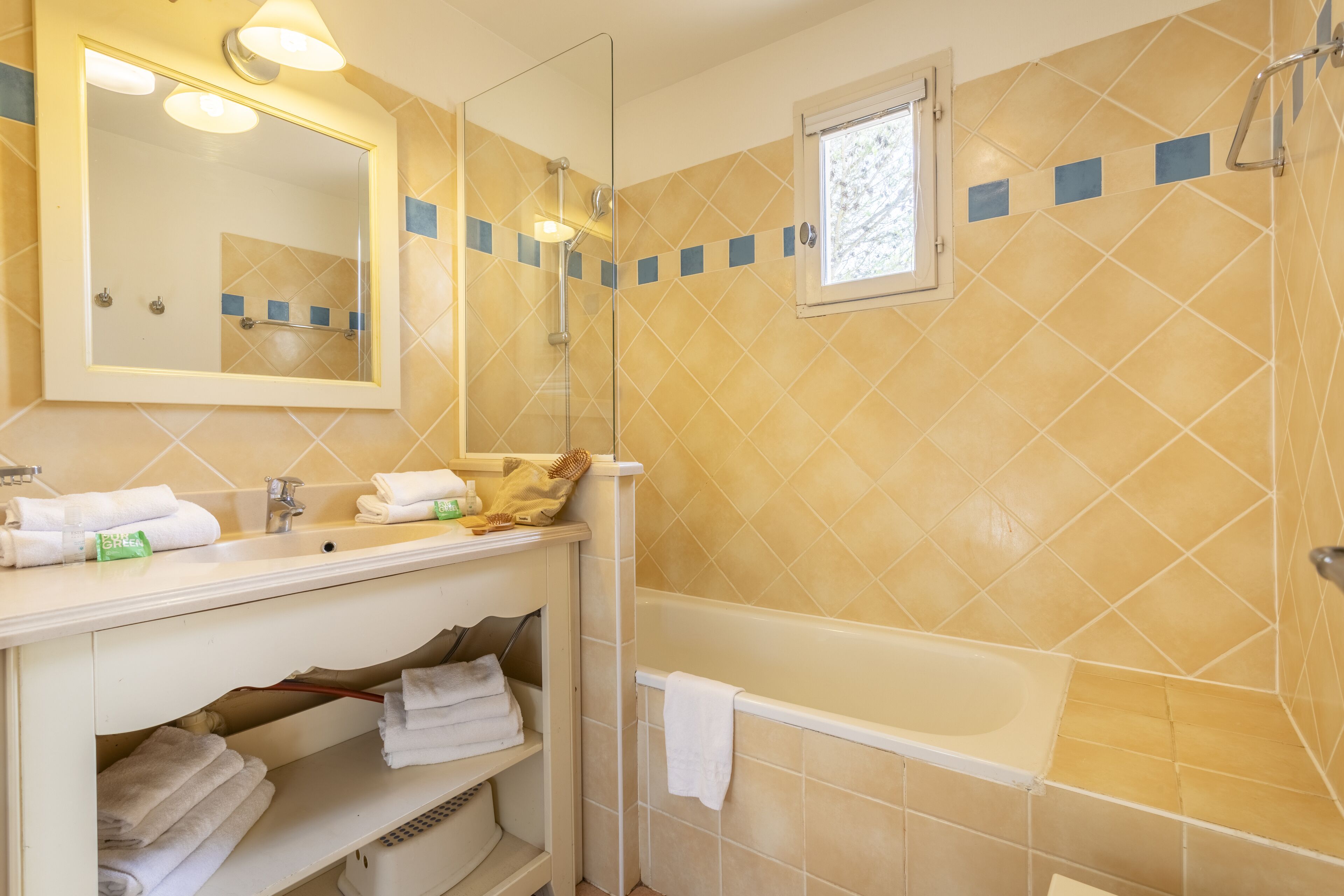 Un baño con bañera, lavamanos, espejo y ducha.