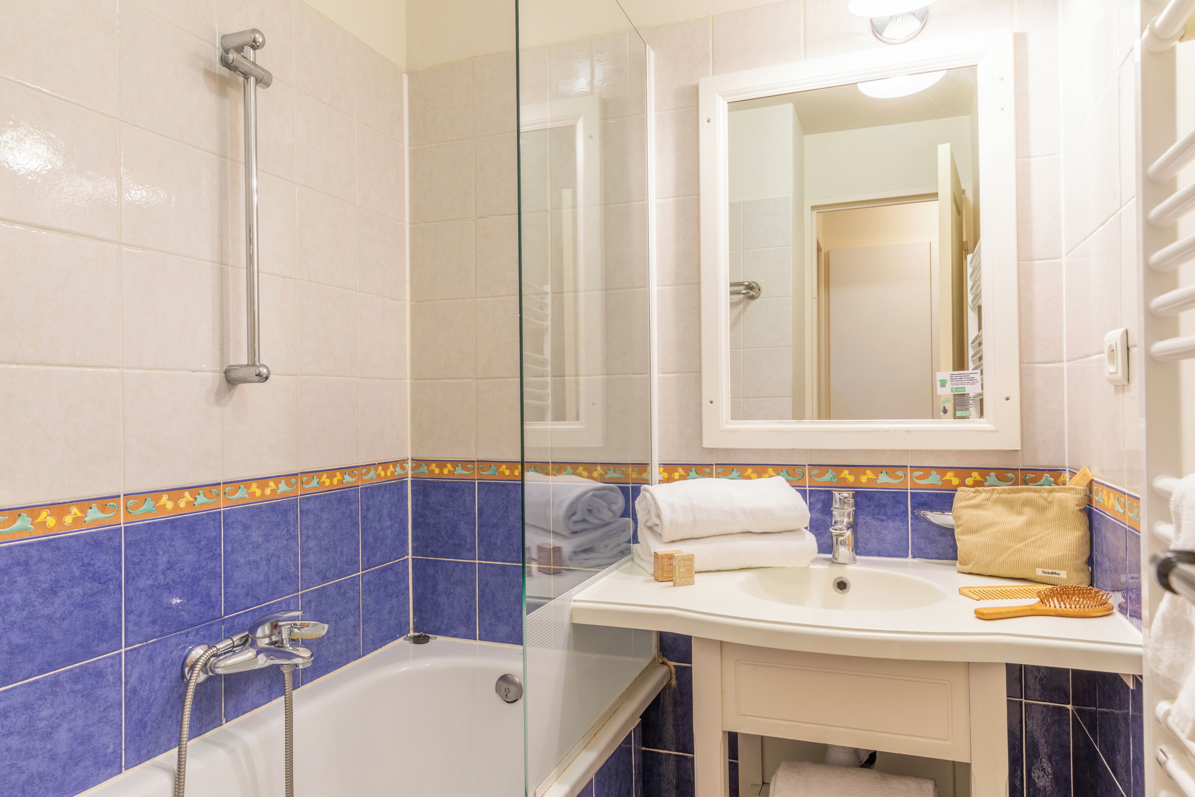 A bathroom with a bathtub, a sink, a mirror, and a towel rack.