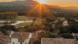 A rural landscape with a sunset, a golf course, and residential buildings with tiled roofs.