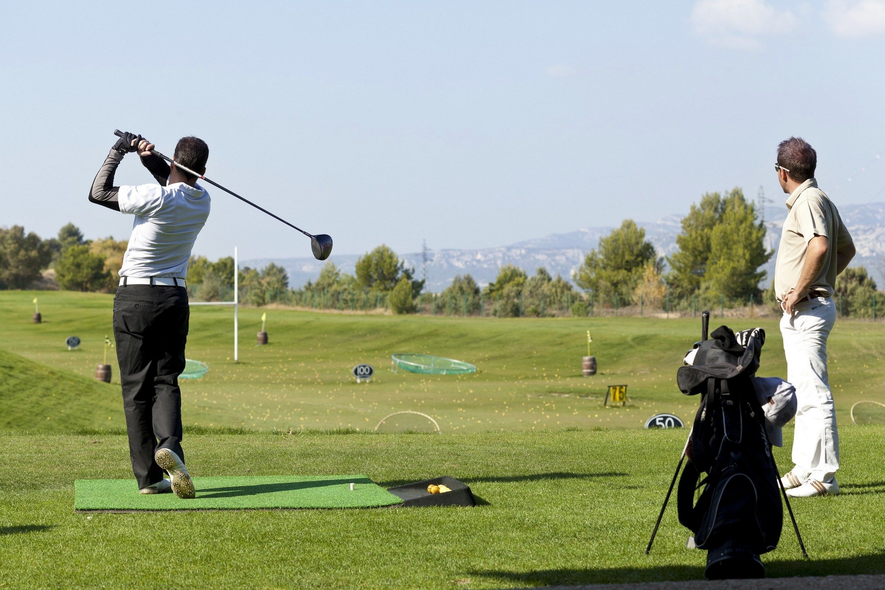 A golf course with a putting green, a flag, and a golf bag.