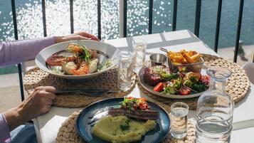 Una mesa dispuesta con platos de comida, una botella de agua y vista al agua.