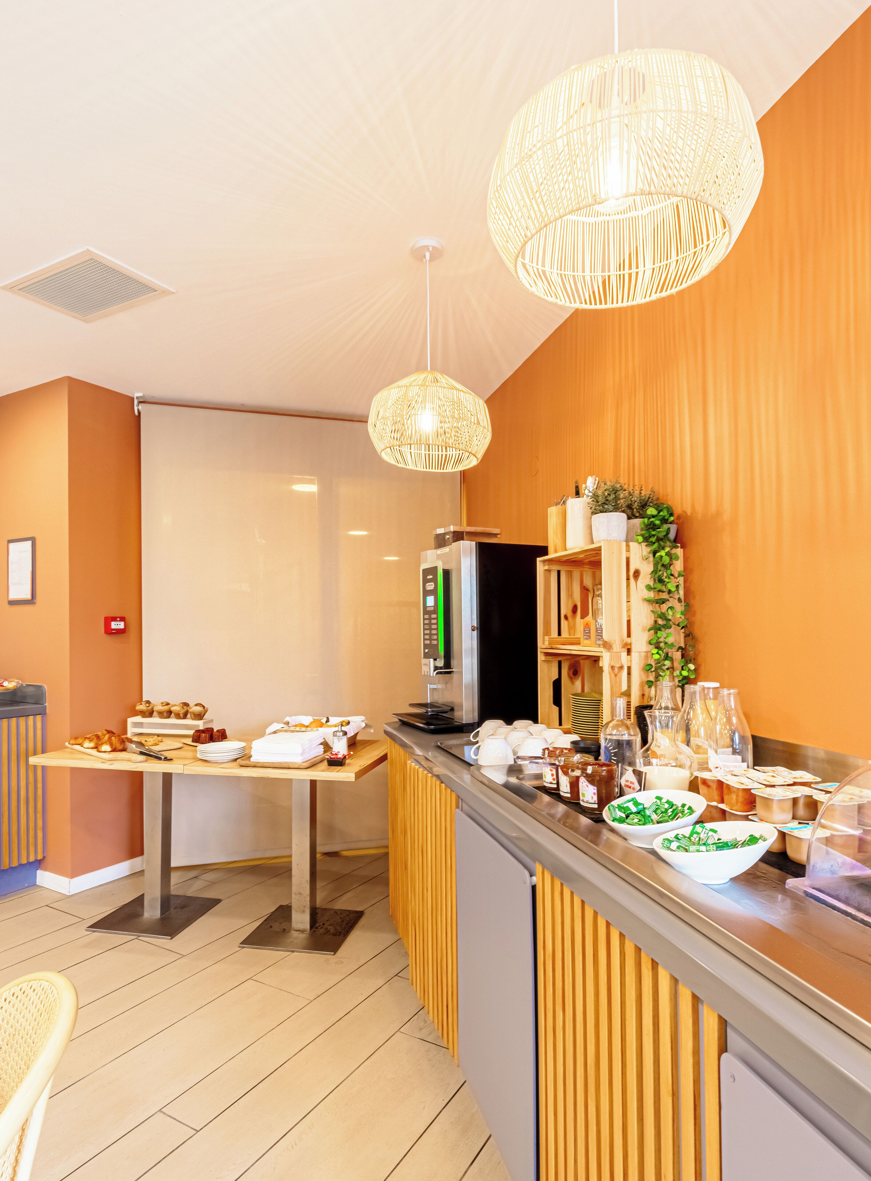A modern kitchen with a buffet setup, including a coffee machine, a refrigerator, and various food items on the counter.