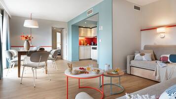 Una sala de estar moderna con sofá, una mesa de centro y un comedor con sillas y una mesa dispuesta para el desayuno.