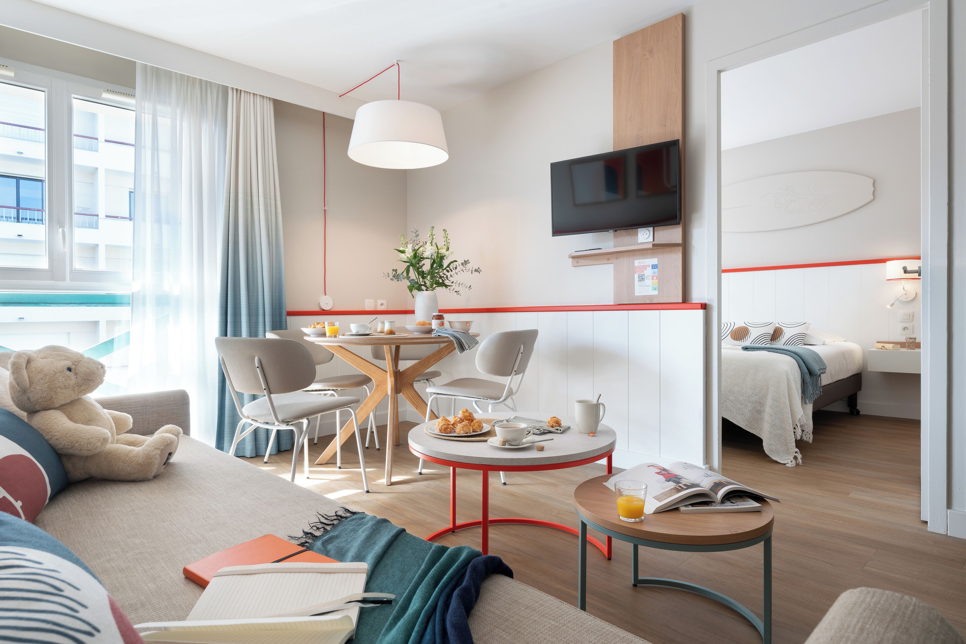 Ein modernes Hotelzimmer mit einer Couch, einem Essbereich, einem Fernseher und einem Bett.
