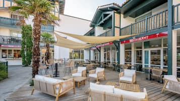 Un espace extérieur aménagé avec des meubles en osier et une terrasse en bois.