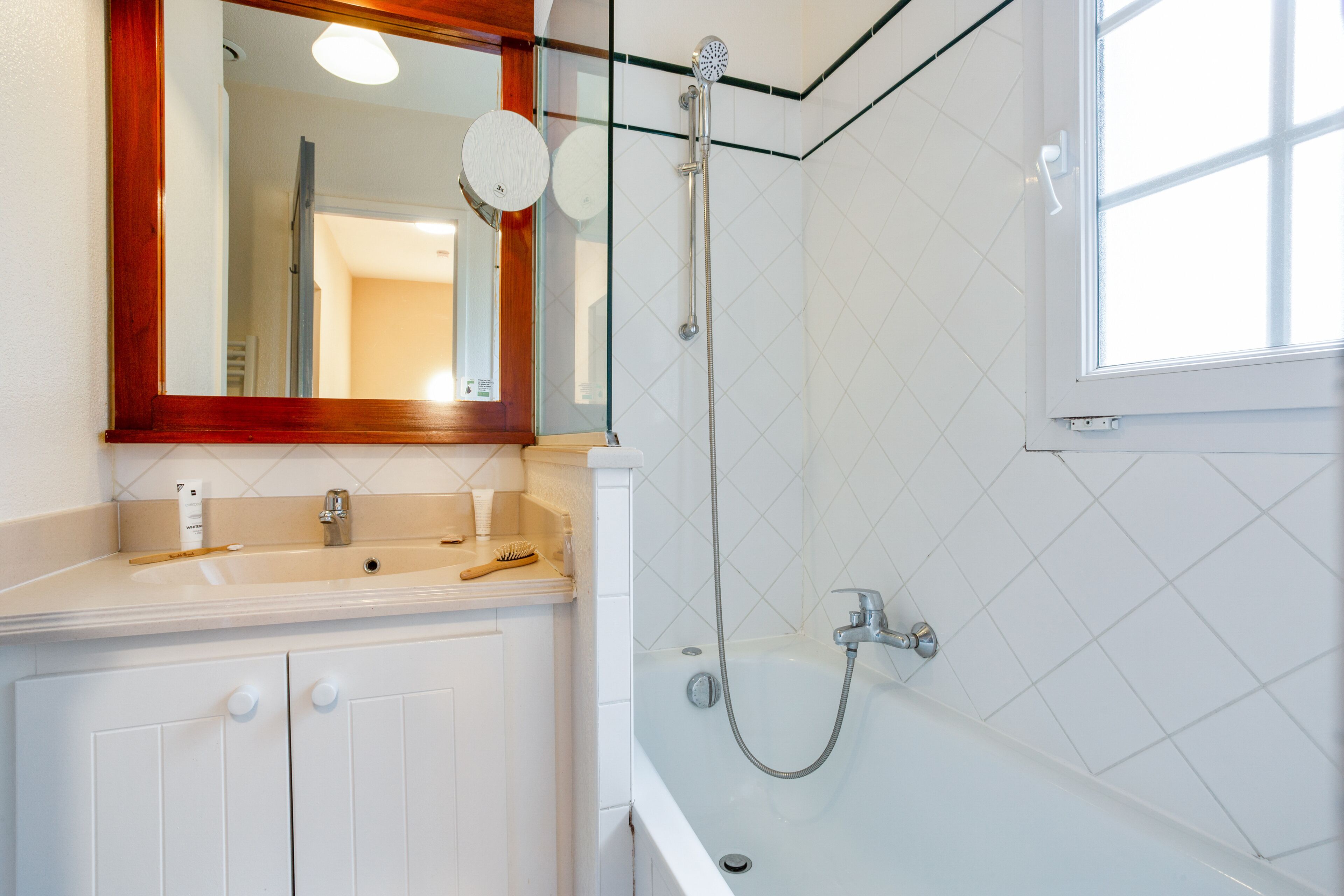 A bathroom with a white sink, mirror, and shower.
