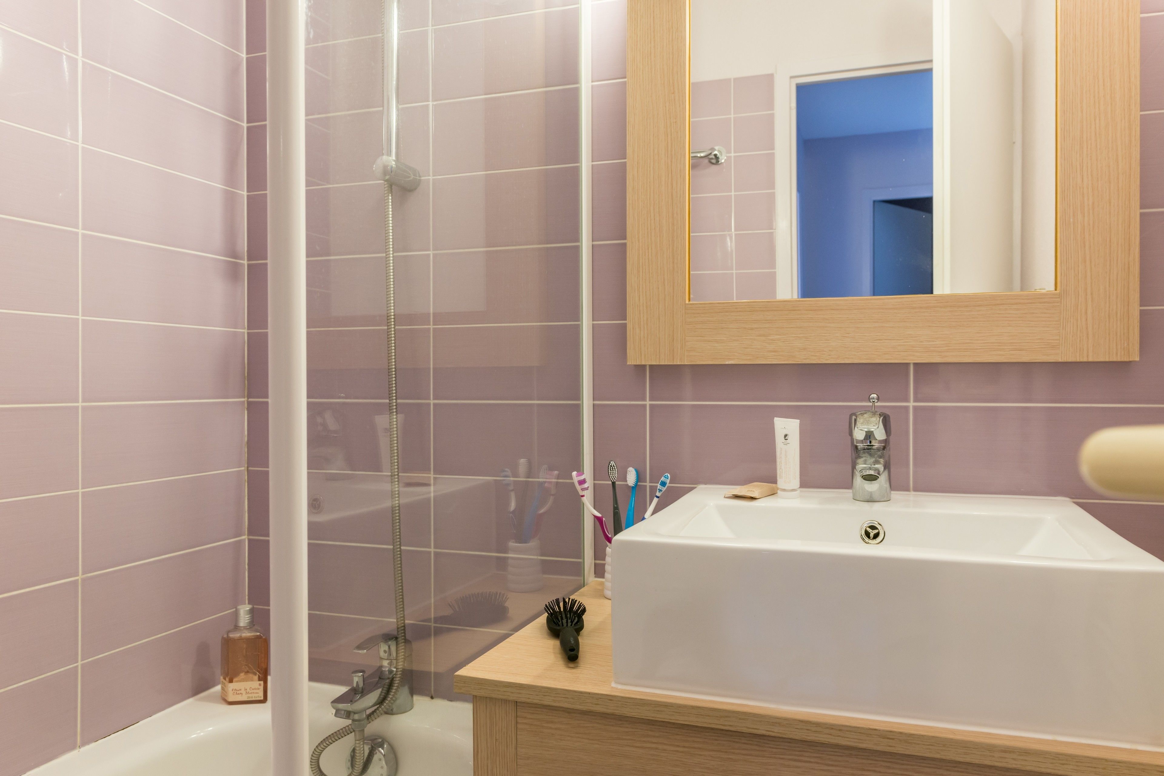 Een badkamer met een douche, wastafel en spiegel.