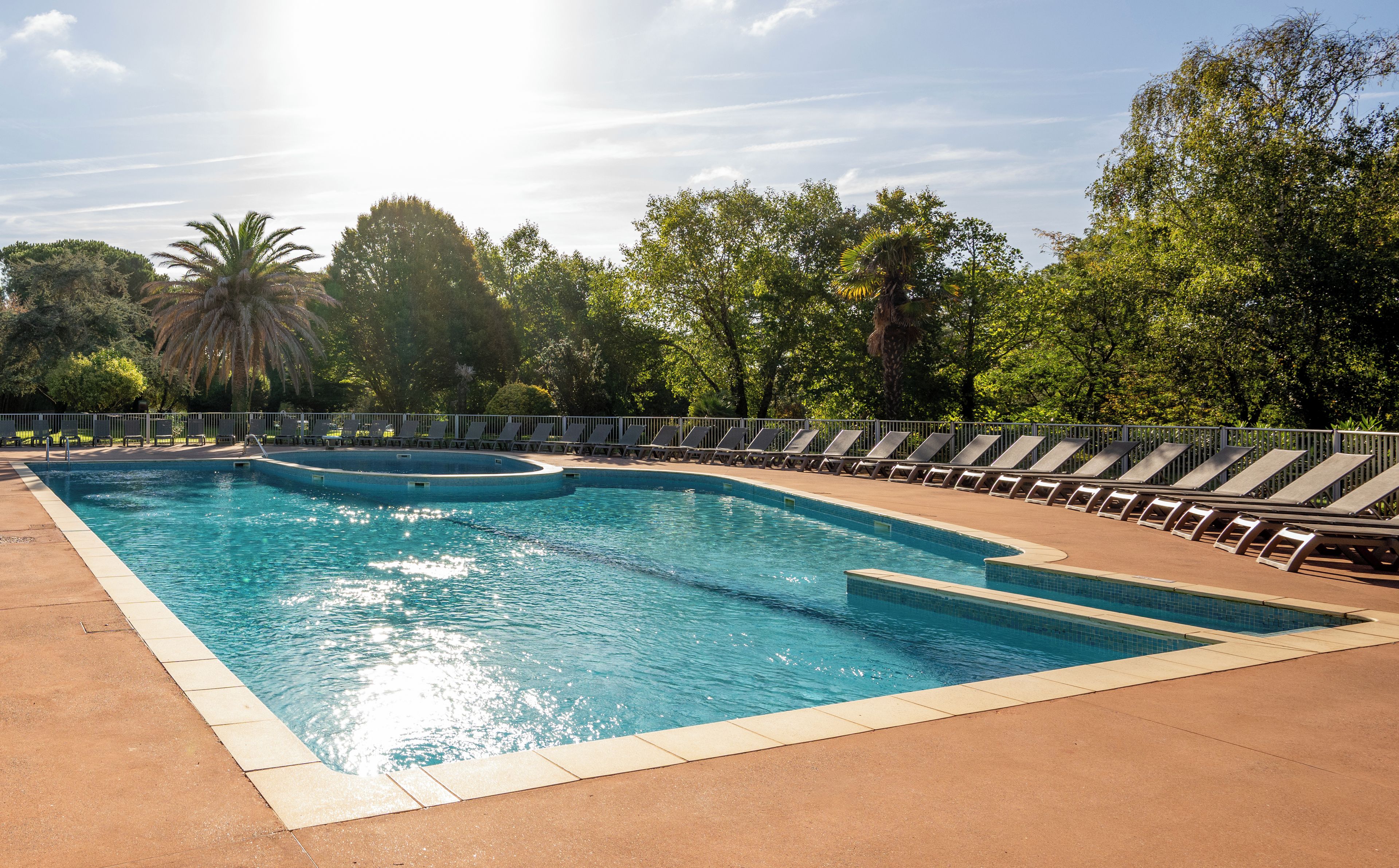 A swimming pool with a sunshade area and lounge chairs.