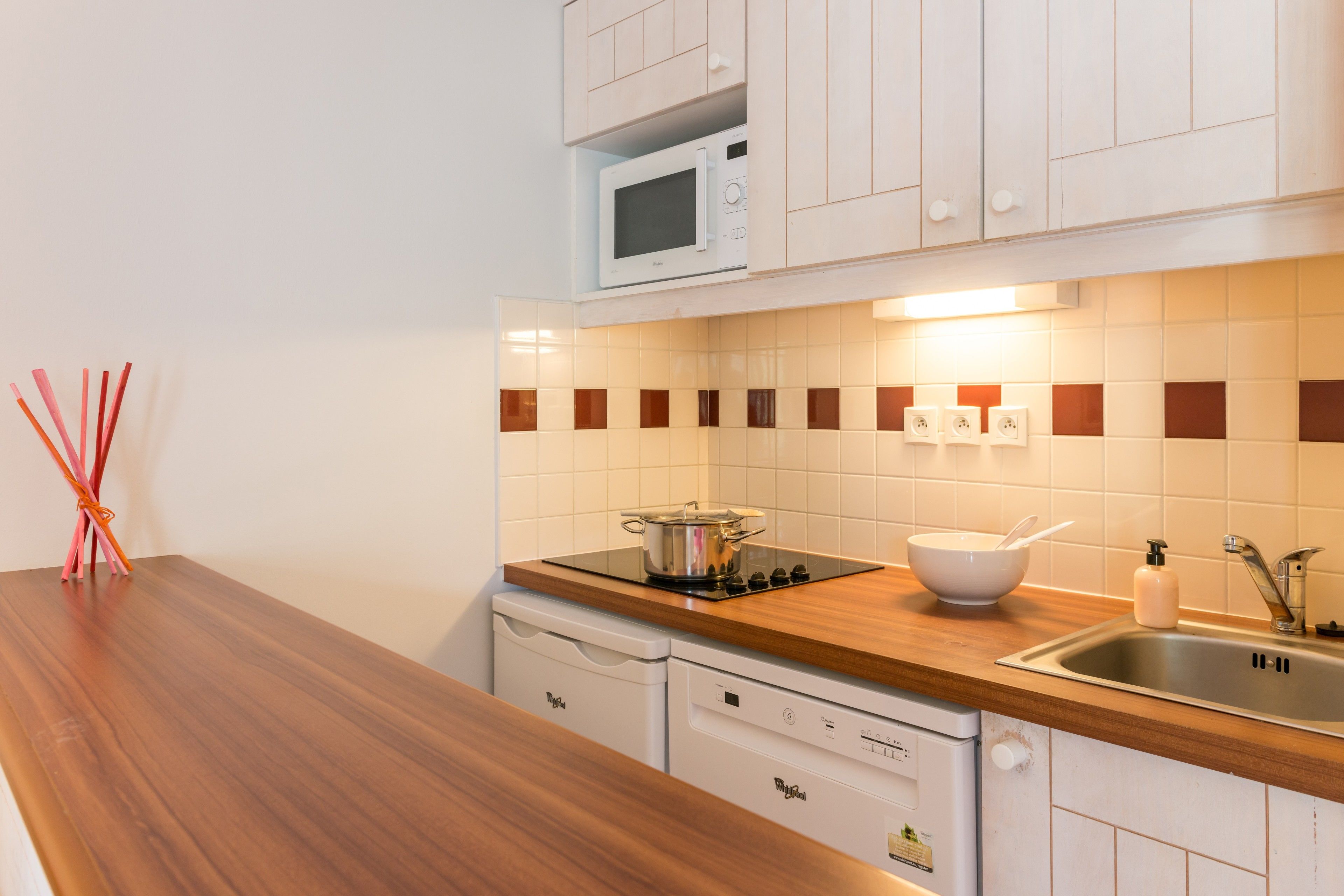 Una cocina con armarios blancos, microondas, estufa, fregadero y encimera de madera.