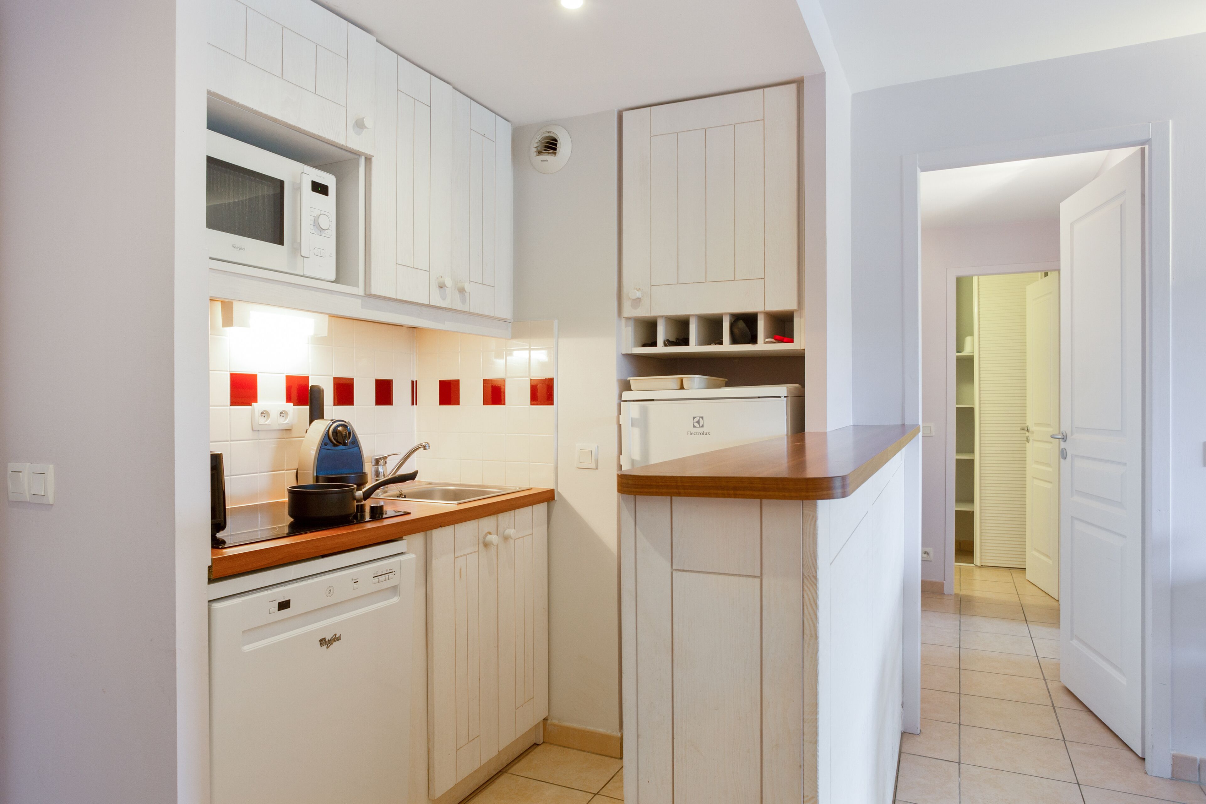 A compact kitchen with white cabinets, a microwave, a sink, and a dishwasher.