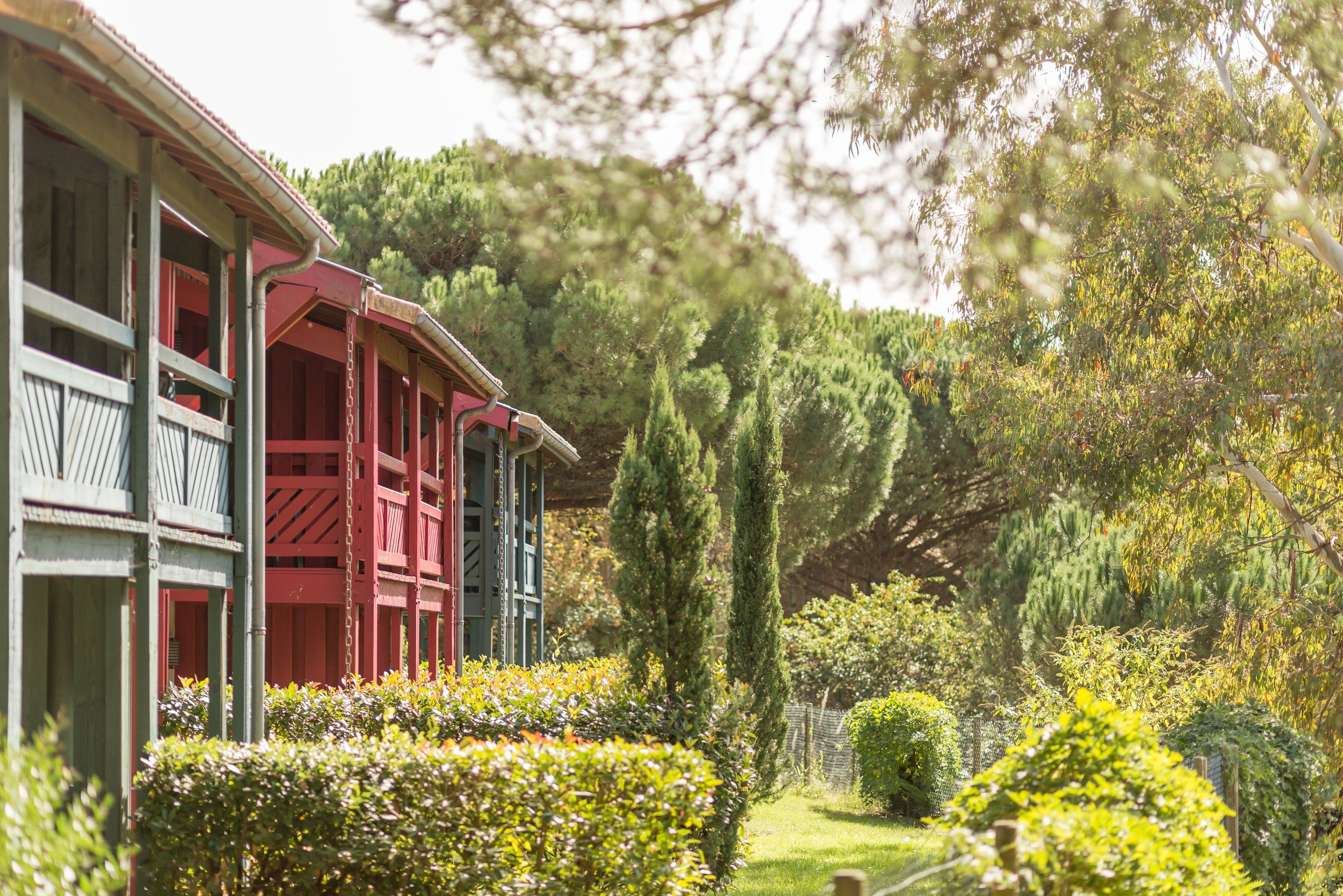 A building with a red and green facade, surrounded by well-maintained gardens and trees.