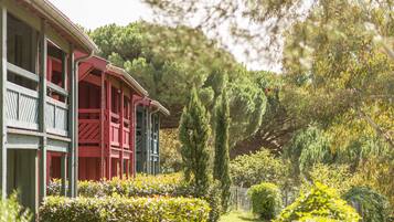 A building with a red and green facade, surrounded by well-maintained gardens and trees.