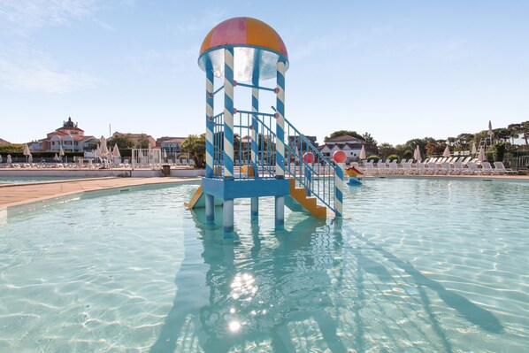 Una piscina al aire libre de temporada, sombrillas, tumbonas