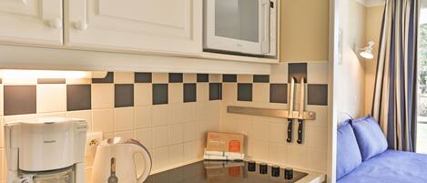 A compact kitchenette with a microwave, coffee maker, and kettle.