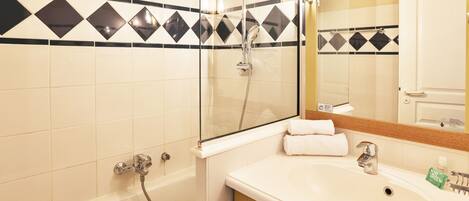 Une salle de bain avec une baignoire, une douche à parois de verre et un lavabo avec un miroir au-dessus.