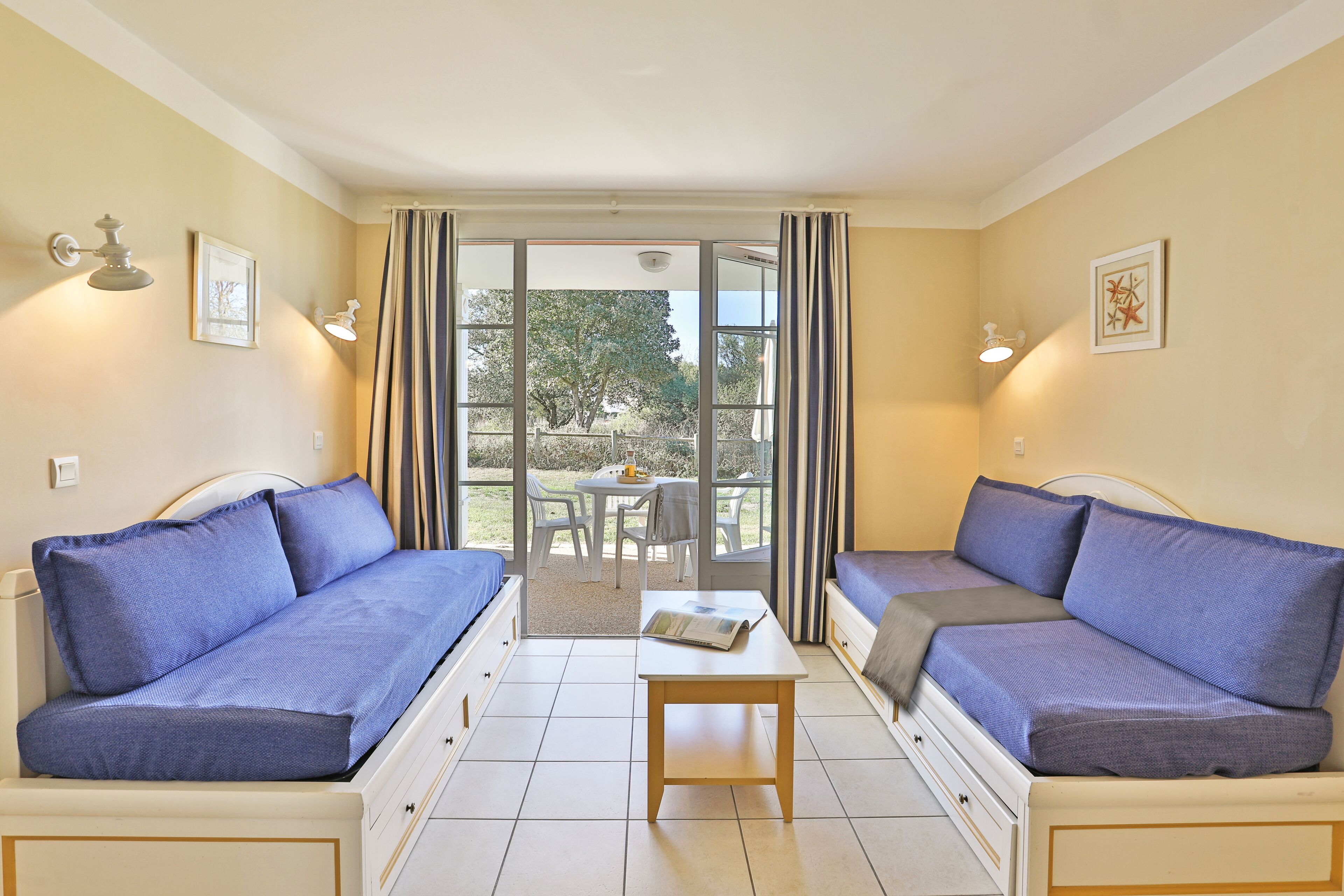 A room with two sofas, a table, and a sliding glass door leading to an outdoor area.