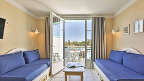 A room with two blue sofas, a small table, and a balcony with a view. - Résidence Pierre & Vacances Le Domaine de Bourgenay (Talmont-Saint-Hilaire)