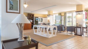 A spacious living area with a white table, comfortable seating, and a bookshelf. - Résidence Pierre & Vacances Le Domaine de Bourgenay (Talmont-Saint-Hilaire)
