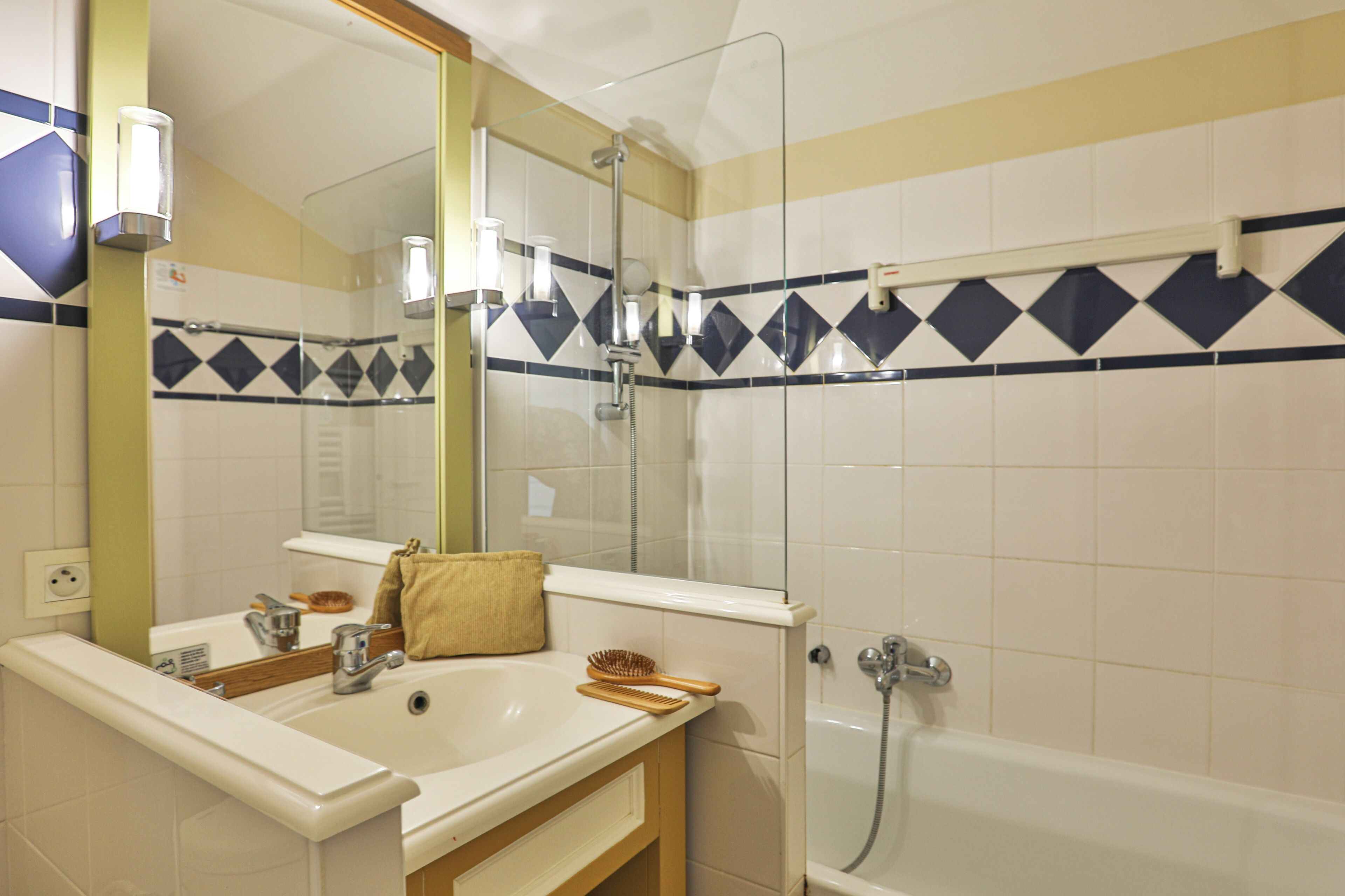 Een badkamer met een wastafel, spiegel en douche.