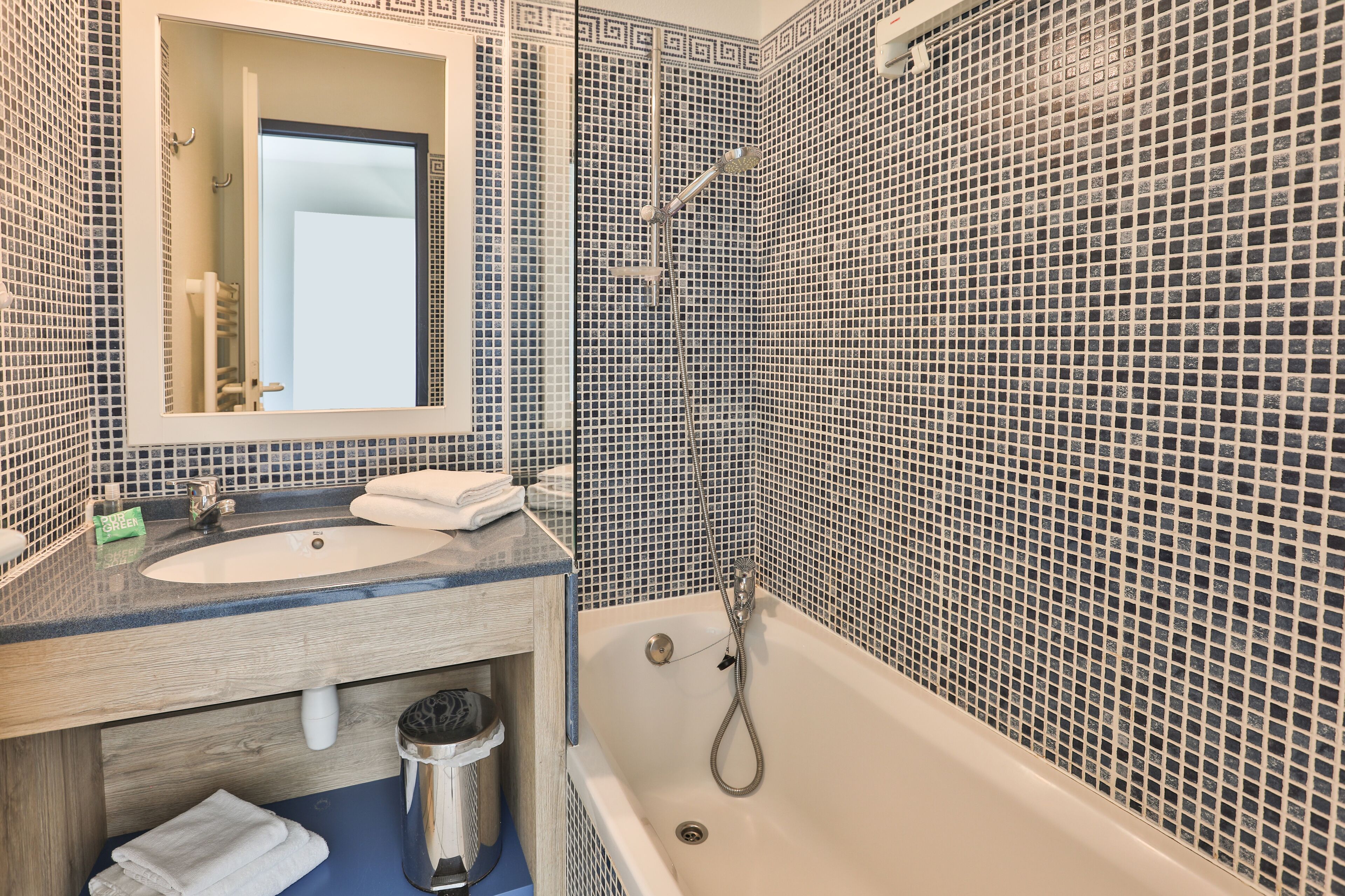 A bathroom with a sink, mirror, and bathtub.