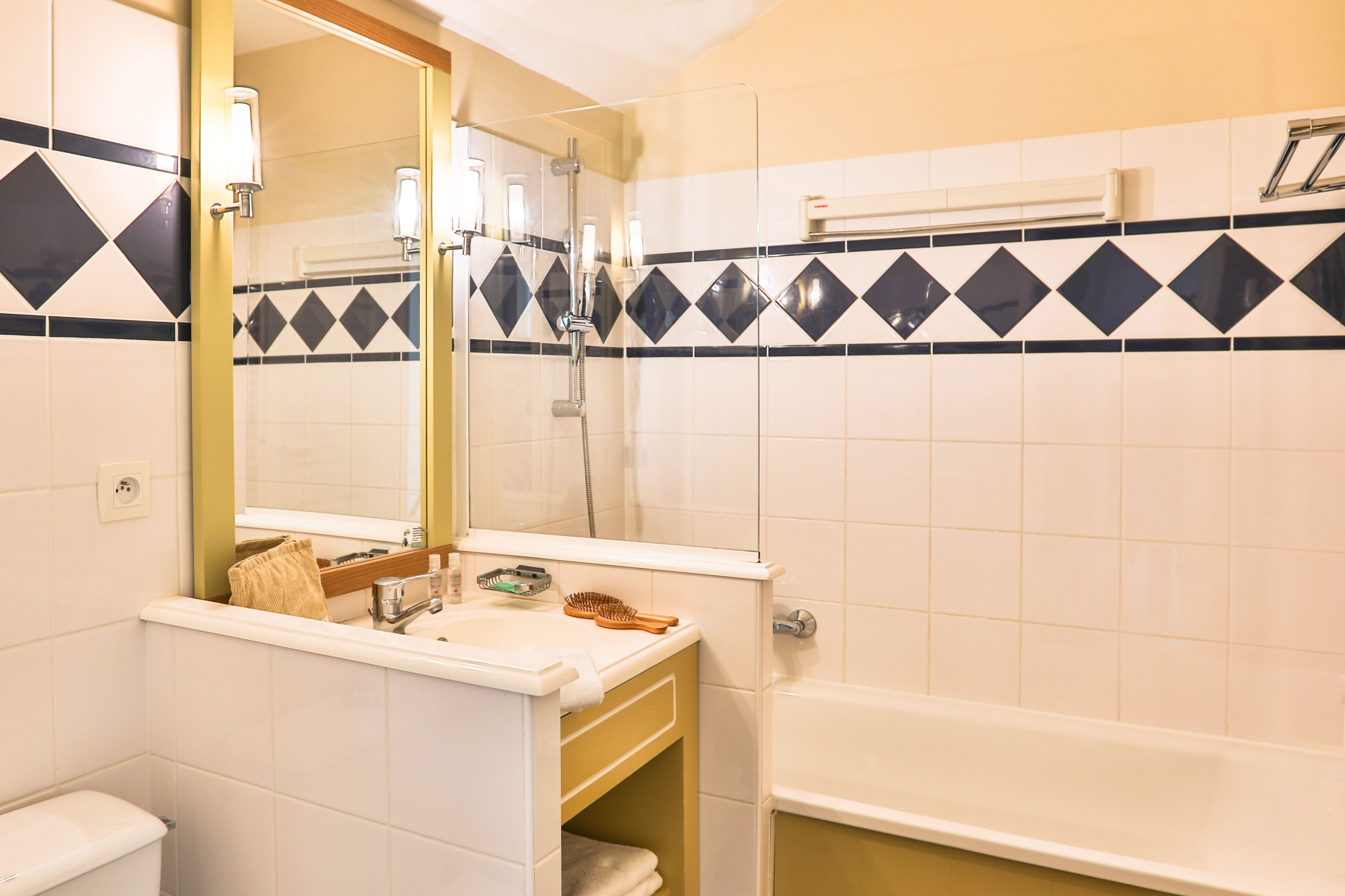 Een badkamer met een wit wastafel, spiegel en douche.