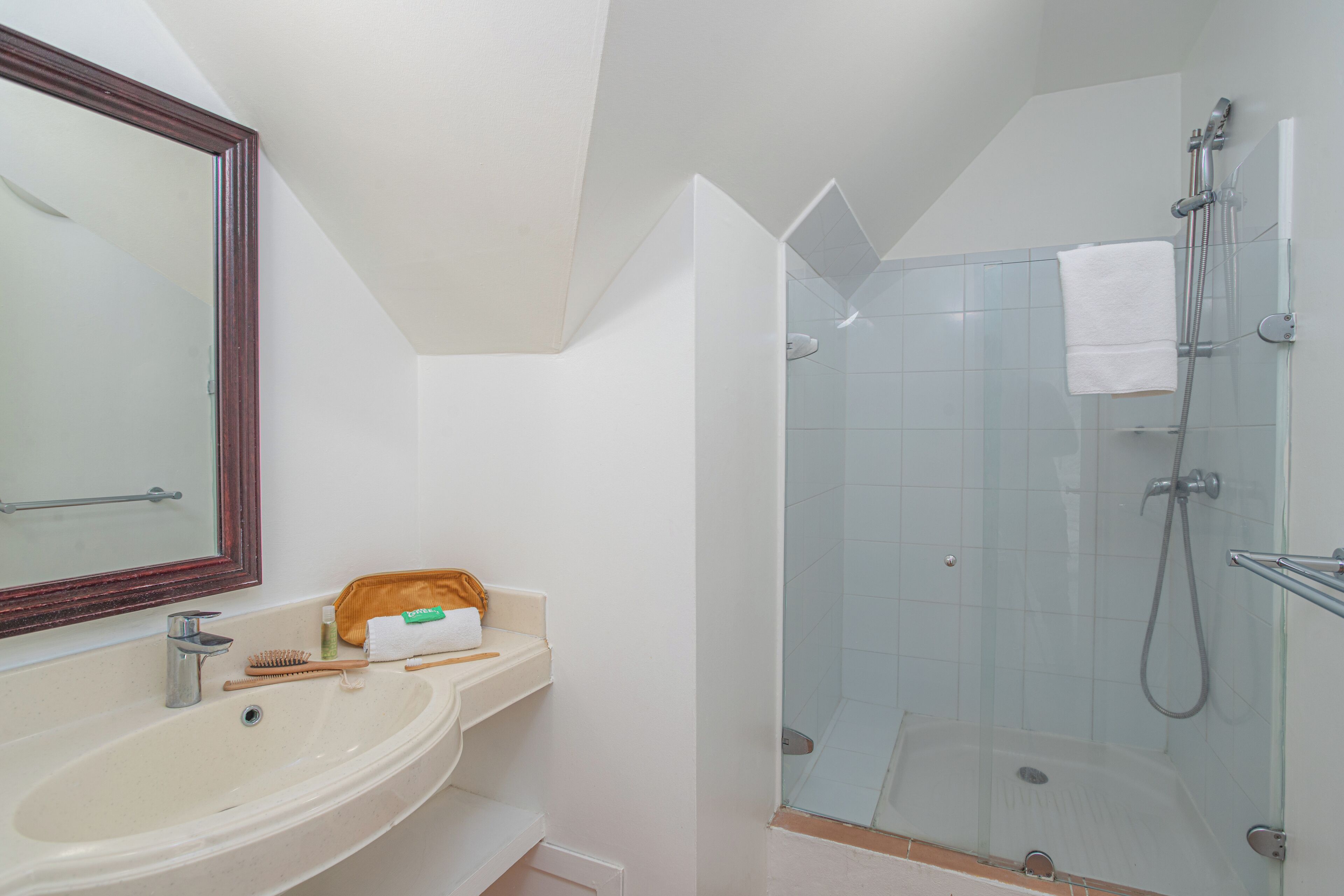 A bathroom with a sink, mirror, and shower.