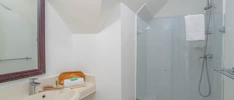 A bathroom with a sink, mirror, and shower.