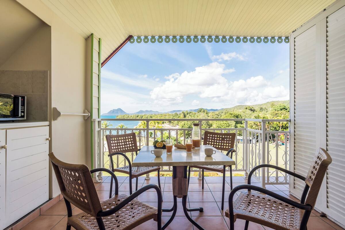A covered patio with a table and chairs, a microwave, and a view of the mountains.