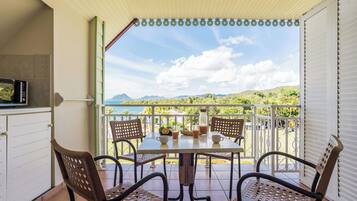 A covered patio with a table and chairs, a microwave, and a view of the mountains.