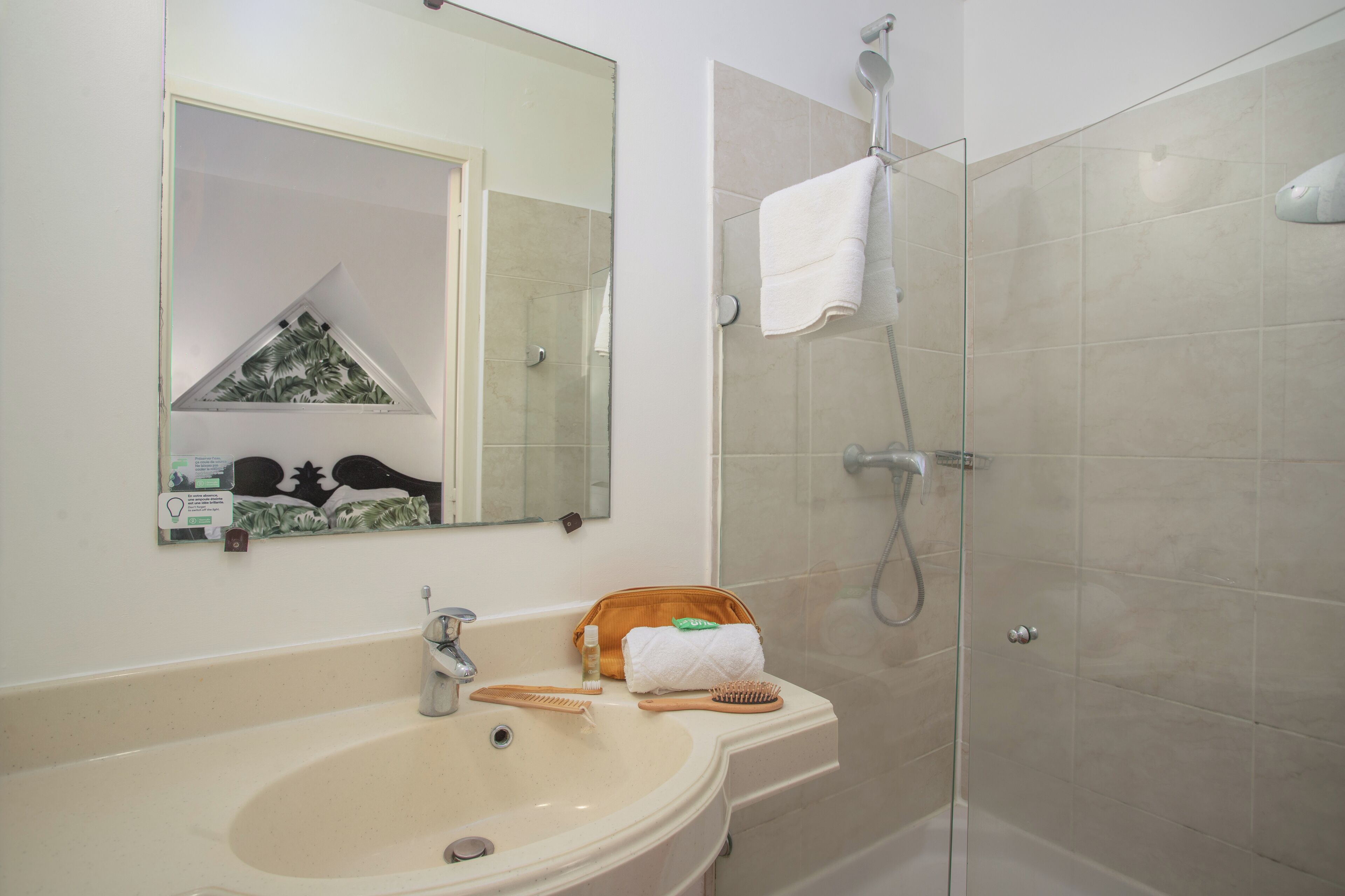 A bathroom with a sink, mirror, and shower.